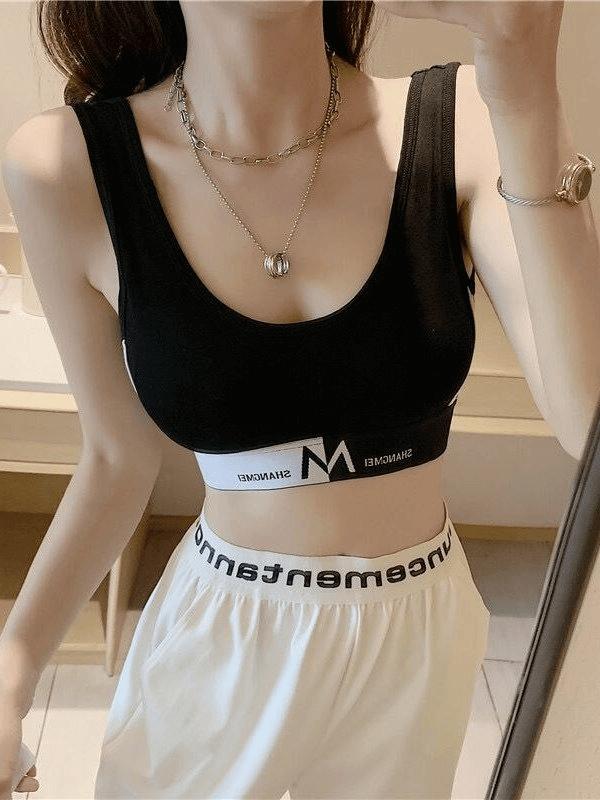 Woman wearing a black seamless sports bra top with white waistband, ideal for workouts and fitness activities.